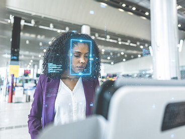 A businesswoman uses facial recognition technology on her smartphone while passing through airport security