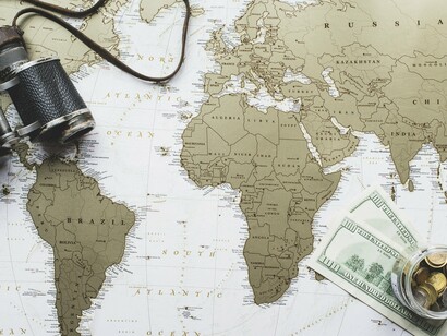 A magnified map of Africa surrounded by money and navigation tools, representing the intersection of wealth, power, and global influence