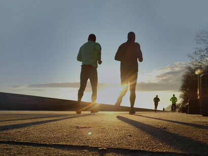 Two friends jogging side by side at sunset as a way to keep in shape and manage their ADHD condition naturally