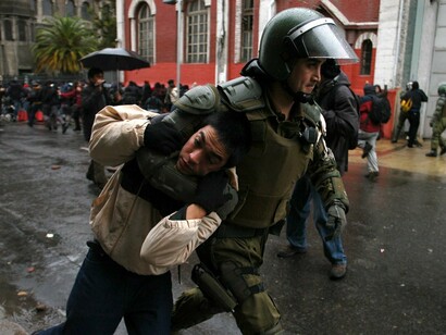 Un carabinero chileno detiene a un joven en una protesta