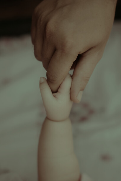Maternità. Mano di bebè che stringe mano adulta