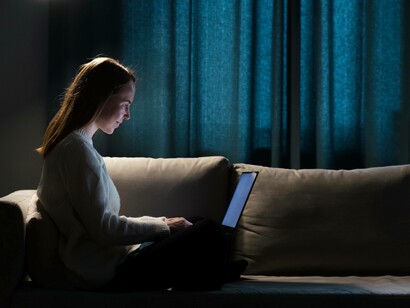 Donna sul divano davanti al computer: "Quando dialoga con noi, questa macchina si comporta come se stesse comunicando con un’altra macchina: riceve dati, li elabora e modifica le proprie risposte di conseguenza"