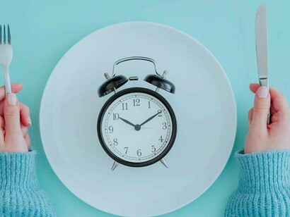 Waiting to break the fast with utensils and a clock on the plate