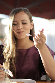 A woman in purple enjoys her meal, taking time to savor each bite