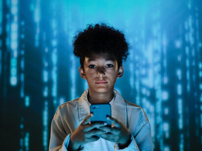 A boy using a mobile phone surrounded by flowing data in a data-driven world