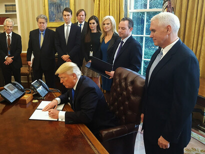 Donald Trump signs orders, surrounded by his ministers