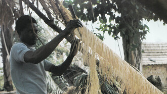 Homme tissant du raphia sur un métier à tisser au Congo