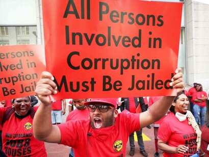 A health worker protest in South Africa where protesters are waving banners reading "all person involved in corruption must be jailed"