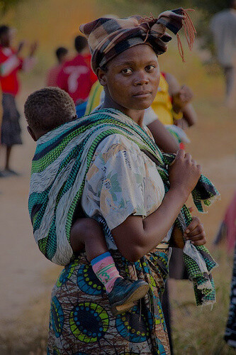 Mãe carrega seu bebê com a capulana