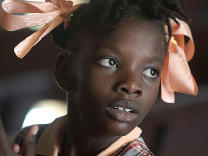 A young Haitian girl with bows tied to her hair