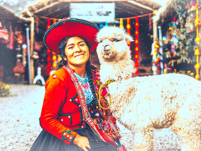 A local Peruvian woman at a market smiles with her llama in Chinchero, Cuzco, Perú