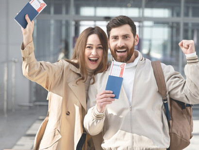 A cheerful couple with passports and documents at the airport, preparing to move abroad in a scenario of skilled migration and brain drain