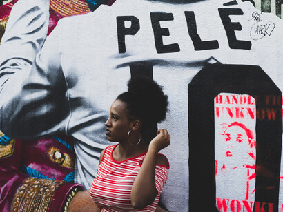 Garota posando em frente a uma arte de rua em homenagem ao rei do futebol brasileiro, Pelé