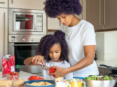 A mother and daughter cooking side by side, reflecting the importance of nurturing independence alongside family connection