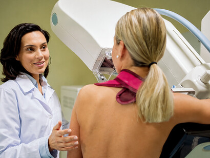 Doctor operating a mammography scanner during a breast cancer screening procedure in a hospital
