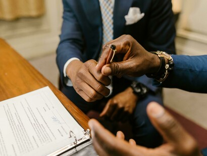 Man handing a pen to another man to sign a contract, close-up