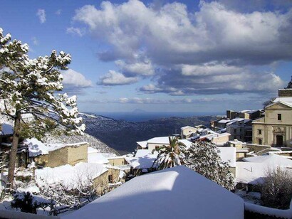 La chiesa di San Luca innevata e nello sfondo l'isola di Filicudi. Foto di Charley Fazio