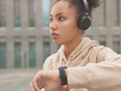 A fitness model in a beige sweatshirt reviews workout results on a smartwatch after outdoor exercise, highlighting wearable devices and smart technology in fitness, emblematic of technological advancements
