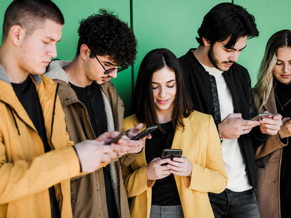 A group of young people scroll through their phones, illustrating how digital devices can replace face-to-face interaction