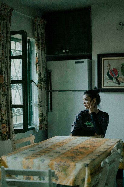 Solitary woman in a dark interior, capturing themes of social isolation, motherhood anxiety, and digital-age tragedy