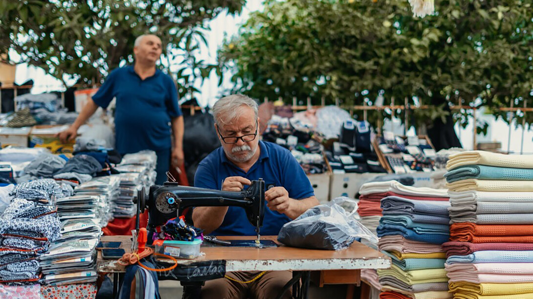 A man sitting at a table, with a gun beside him and a pile of laundry nearby, Turkey