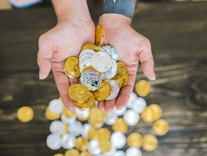 Foto de close-up de pessoa segurando Bitcoins prateados e dourados