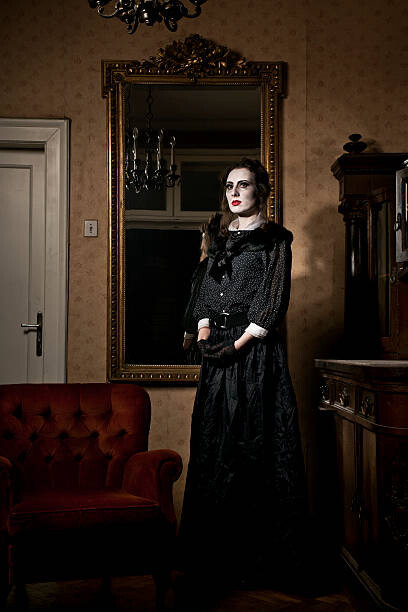A haunting figure of a woman stands by an armchair, framed by the reflection in a vintage Victorian mirror