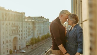An elderly couple on a balcony, captured in a quiet moment as they share a kiss