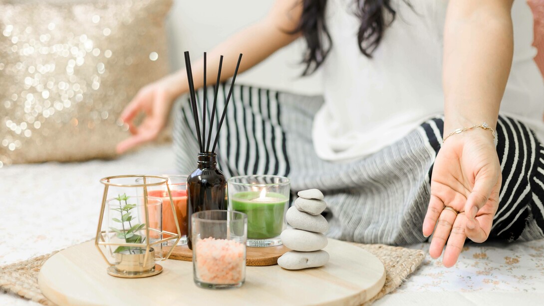 A woman assuming the yoga pose with her incense, candles, and other mediation-friendly trinkets