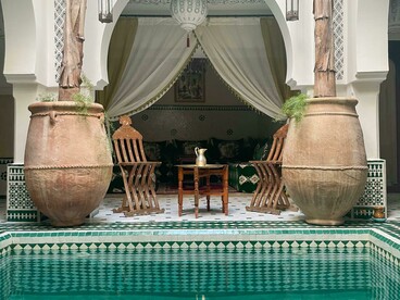 A white and blue tiled swimming pool set within the interior courtyard of a traditional riad in Marrakesh, Morocco