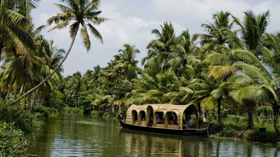 A houseboat with tourists, snaking its way through the backwaters of Kumarakom