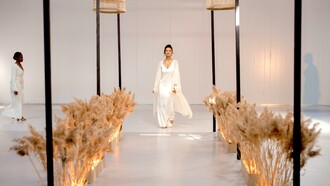 Uma modelo usando um vestido branco andando na passarela