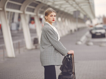 Happy female traveler walking through the airport with her luggage, preparing to move abroad
