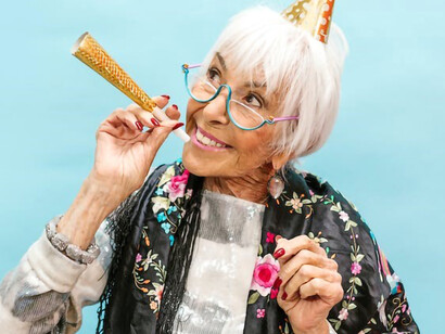 In honor of her birthday, a spirited elderly woman is overflowing with happiness, savoring the richness of life and cherishing every delightful moment