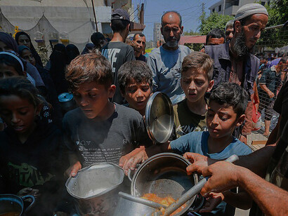 Displaced Palestinians gather in Deir al-Balah, Gaza Strip, to receive food assistance, highlighting the ongoing humanitarian needs of civilians affected by conflict and displacement