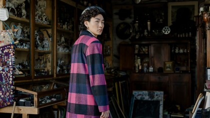 A person wearing a bold checkered coat while exploring a flea market, representing the influence of timeless fashion in a rapidly changing industry