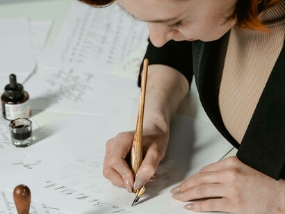 A woman carefully writing down her thoughts in her memoir book