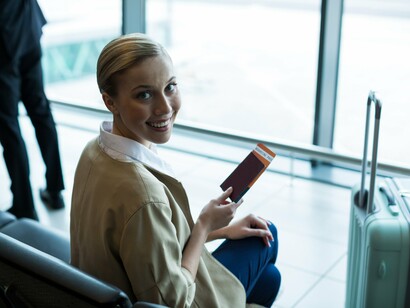 With a carry-on by her side and a bright smile, she embodies the article’s message of balancing comfort and efficiency to enhance the travel experience