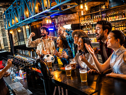 Enthusiastic football fans watching a game and enjoying drinks in a lively sports bar