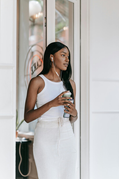 A woman holds a coffee in hand, surrounded by the inviting ambiance of a cozy café