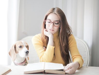 A young woman studying, with her dog next to her