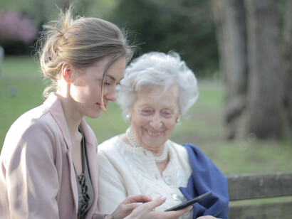 A daughter explaining to her elderly mother how to use a smartphone