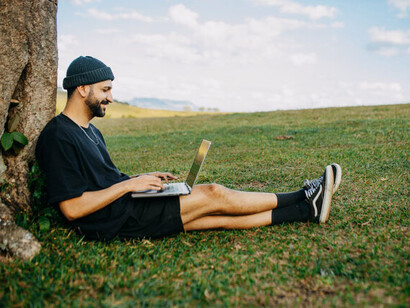 Profisisonal trabalha em seu computador em uma área verde