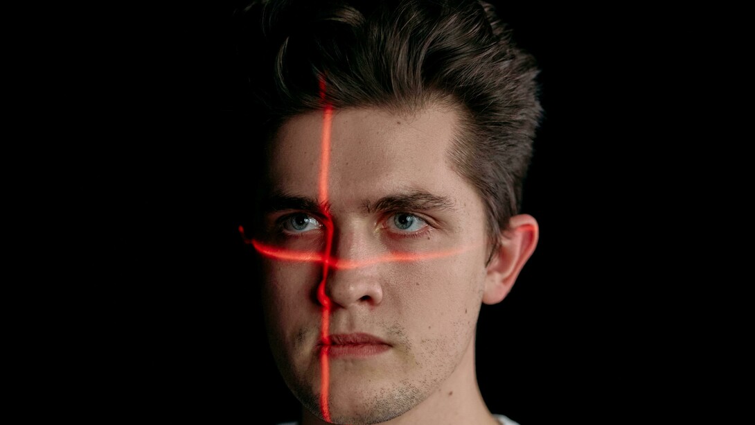Portrait of a man with laser lines on his face, symbolizing facial recognition technology