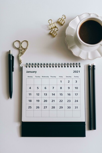 A desk calendar sits beside a black click pen