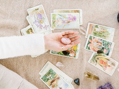 A woman holds a crystal over a set of destiny cards