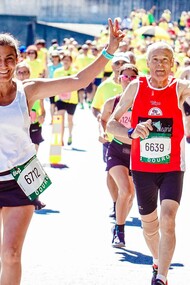 A group of marathon runners approaching the finish line, looking happy and proud to have completed the run