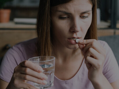 Effective strategies for managing food sensitivities as a young woman takes medicine with a glass of water, navigating dietary restrictions with ease