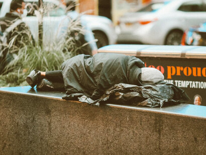 A homeless man sleeping on the sidewalk in a city