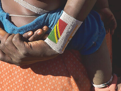 In the tender embrace of his mother, an infant endures a bittersweet reality, Maasai, Tanzania